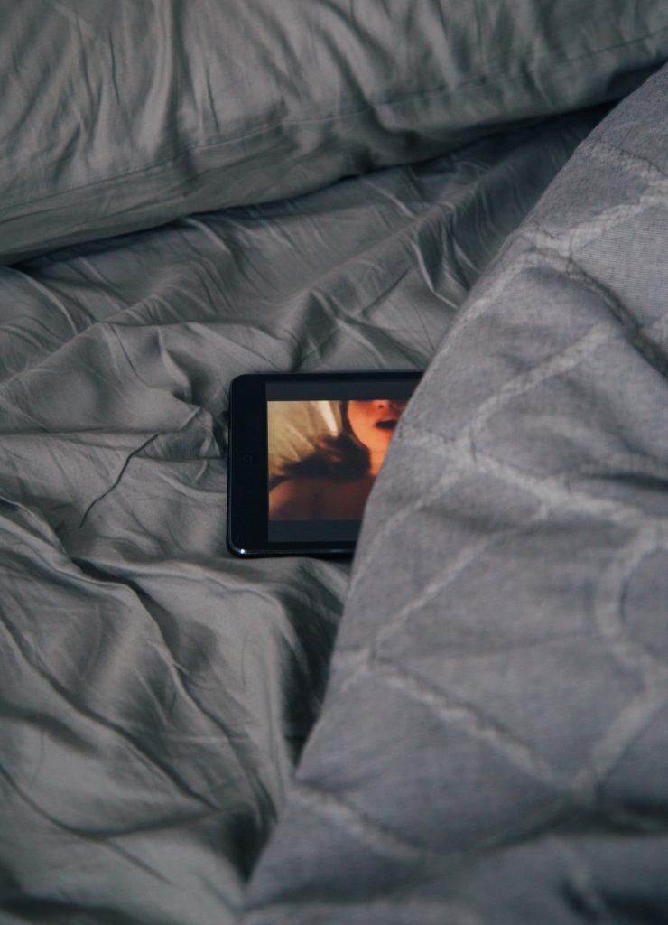 A phone showing pornography under a blanket